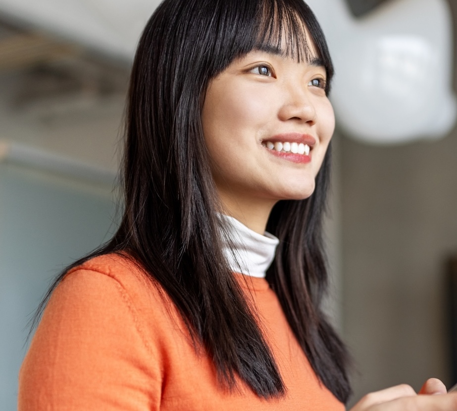 a person using their smartphone, looking away from the phone with a big smile and feeling happy